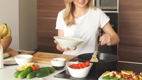 Angenehme junge Frau bereitet Abendessen in einer Küche vor Konzept Kochen