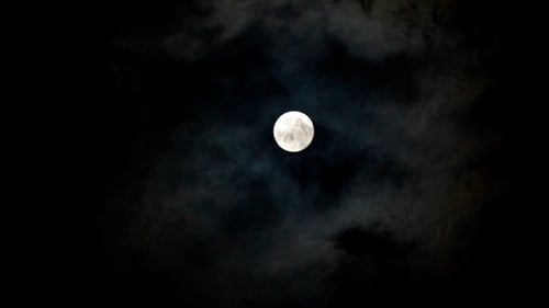 Full Moon Shines Through Dark Clouds at Night