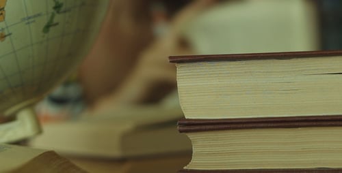 Stack of Books with Globe and Person Reading