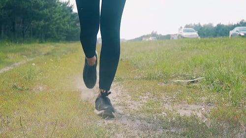CU Slow Motion Lowangle Shot Young Girl Goes in for Sports in the Morning Runs Along a Pine Forest