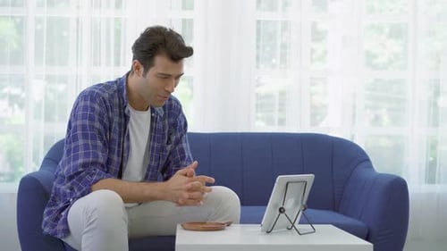 Young Man Video Calling With Tablet on Couch