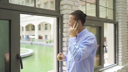 Young Adult Talking on Phone Near Window