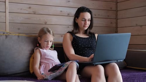 Mother Works From Home While Child Uses Tablet PC