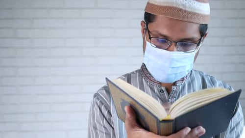 Muslim Man with Face Mask Reading Holy Book of Quran