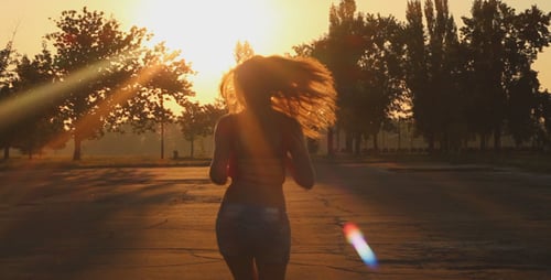 Woman Running at Sunset in a Tree-Lined Park