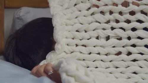 Mulher bonita preocupada se escondendo debaixo do edredom na cama