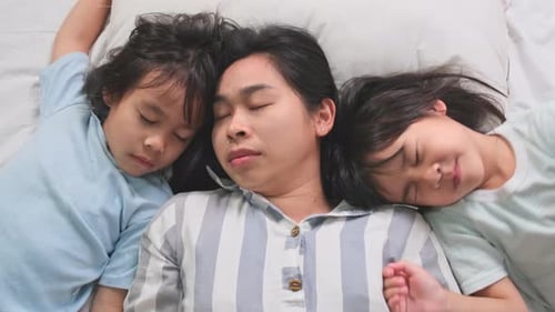 Mother and Children Sleeping Peacefully on Bed