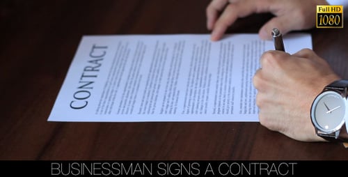 Man Signs a Contract in the Workplace