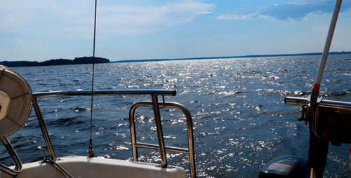 Motorboat Speeding Across Sparkling Lake Water on Sunny Day