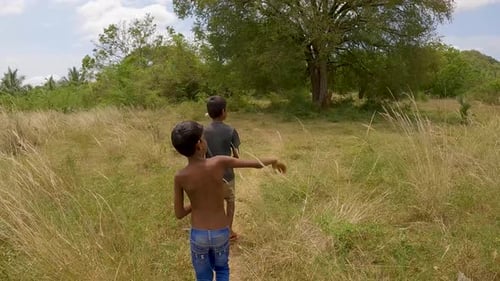 Zwei südasiatische indische Dorfjungen gehen durch Grasland