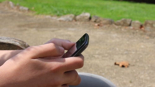 Hands Using Smart Phone Device Outdoors on Bench