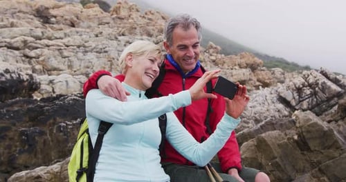 Couple Smiling and Taking Selfie on Rocky Beach