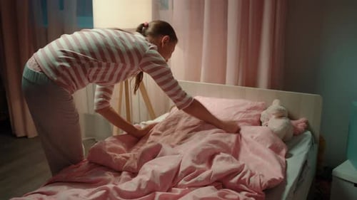 Mother Tucking Young Child Into Bed at Night