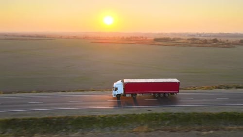 Aerial View of Semitruck with Cargo Trailer Driving on Highway Hauling Goods in Evening