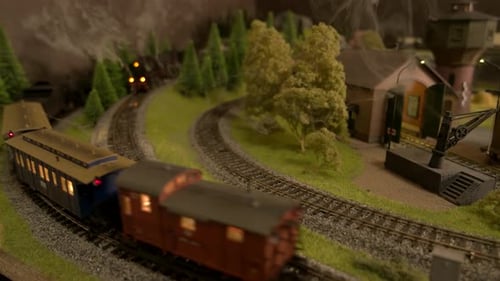 Modelo em miniatura de trens a vapor que se movem pela floresta.