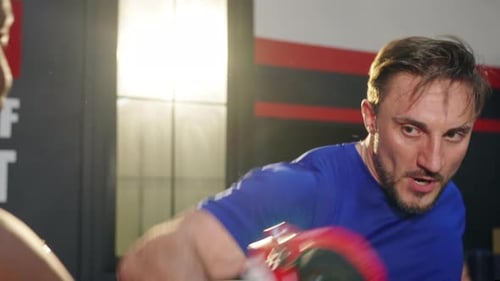 4K Caucasian man practicing boxing exercise with male sport trainer at gym.