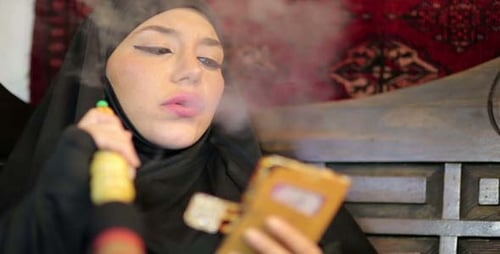 Woman in Headscarf Smoking Hookah