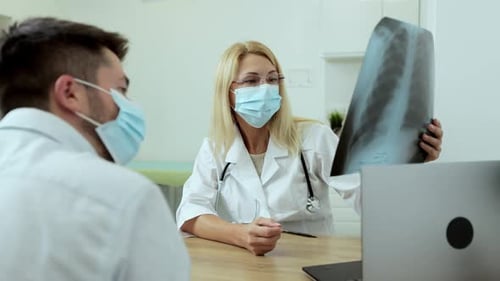 Medical Physician Doctor in Medical Mask Specialist Showing Xray Image of Lungs to Patient