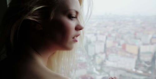 Woman Looking Through Window To City View