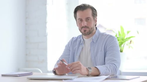 Confident Young Man Smiling at Camera in Office