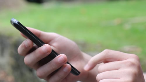 Hands Using Smartphone Touchscreen Technology in Daylight