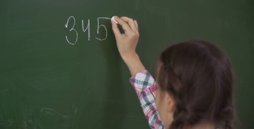 Child Writes Math Equation on Chalkboard