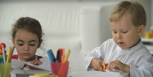 Children drawing and cutting at bright table