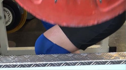 Person Squats with Weight Plates in Gym