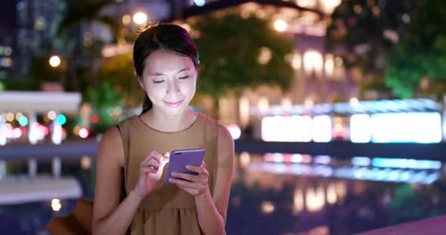 Une femme utilise un téléphone portable en ville la nuit
