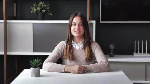 Woman Gives Presentation to Camera at Table Indoors
