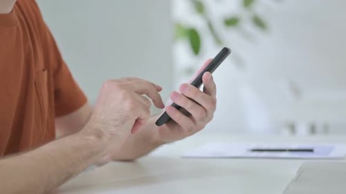 Close Up of Young Man Browsing Internet on Smartphone