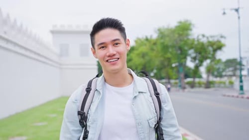 Mochileiro asiático atraente andando pela bela estrada na cidade.