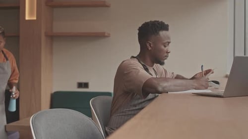 Black Waiter Doing Calculations in Restaurant