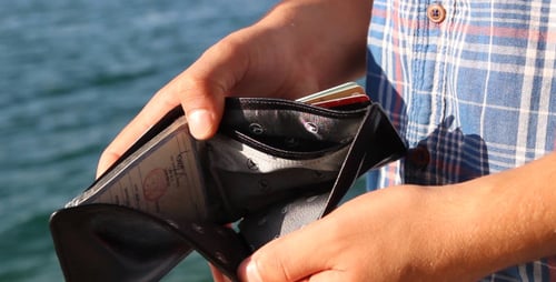 Young Adult Opening Black Wallet by the Water