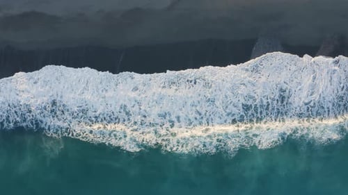 Aerial view of ocean wave splashes into the sand coast