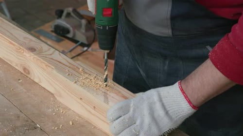 Craftsman Drilling Holes in Wood at Workshop