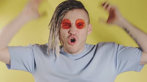 Hombre gritando emocionado enojado con gafas de sol, camiseta azul.