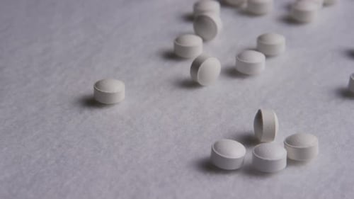 White Pills Scattered on White Surface
