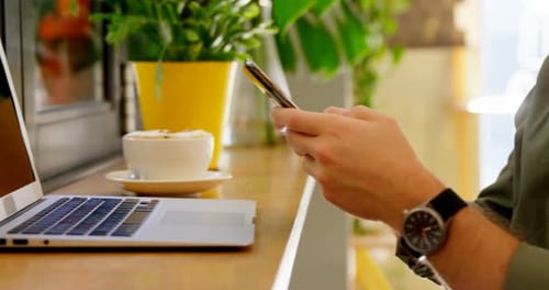 Nahaufnahme eines Mannes mit Handy am Tisch