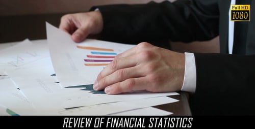 Man Reviews Business Data in Charts and Graphs
