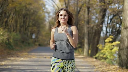 Woman Jogging on a Leafy Path in the Autumn