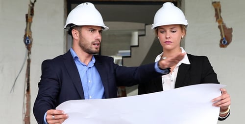Architects Reviewing Construction Blueprint on Building Site