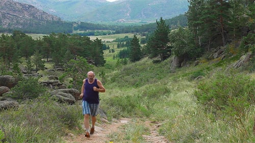 Man Jogs Down a Dirt Path in Mountains