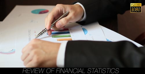 Man Reviews Financial Charts with Pen in Office