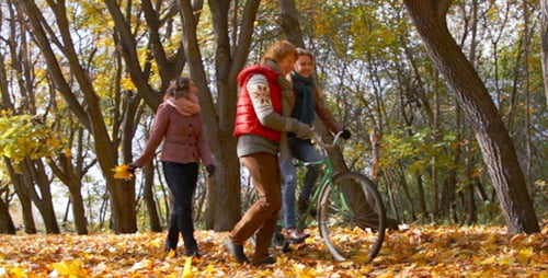 Friends Walking With Bicycle Through Autumn Leaves