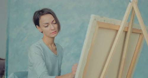 Woman Artist Paints on Canvas Indoors