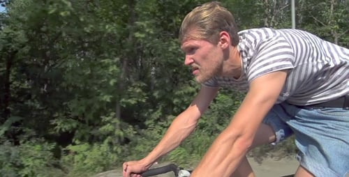 Man Riding Bicycle on Road with Green Trees