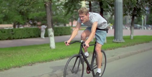 Young Adult Bicycling on City Street on Sunny Day