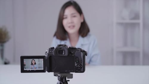 asian woman or beauty blogger with brush and camera recording video and waving hand