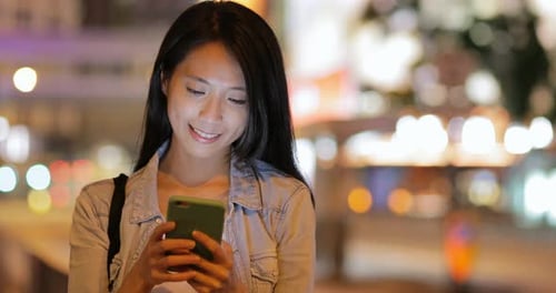 Woman using mobile phone at night